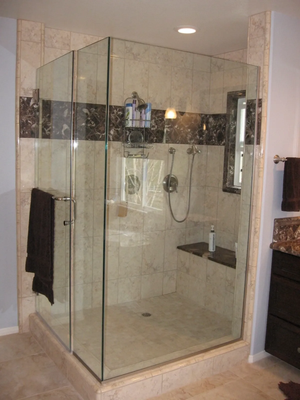 New frameless-glass corner shower with marble-look tile