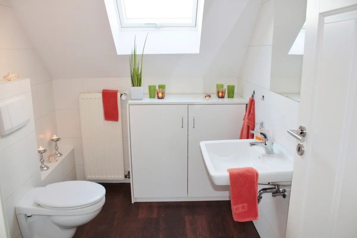 Compact bright bathroom with a pedestal sink beneath a skylight