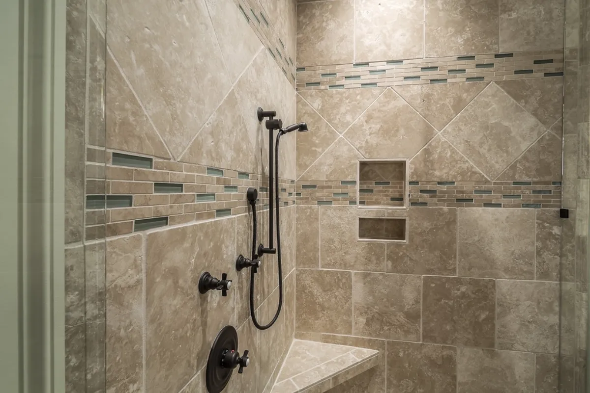 Custom travertine-tiled walk-in shower with a niche and bench