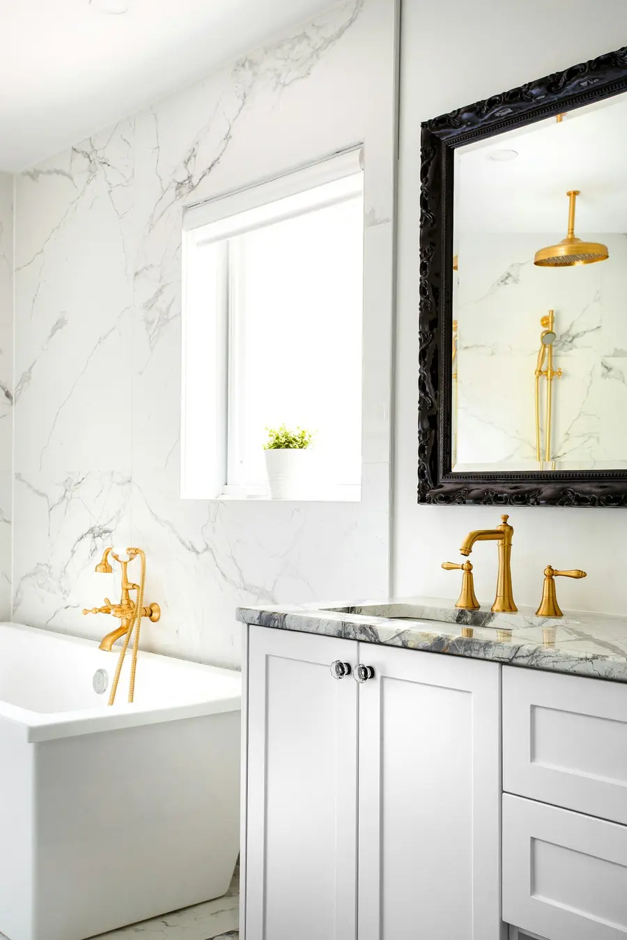 White-and-marble bathroom with a freestanding tub and brass fixtures