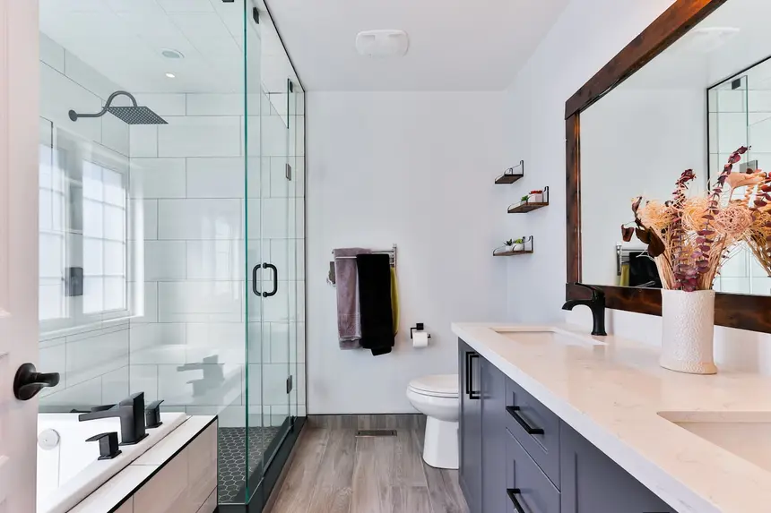 Renovated bathroom with a white subway-tile shower, gray shaker vanity, and a soaking tub