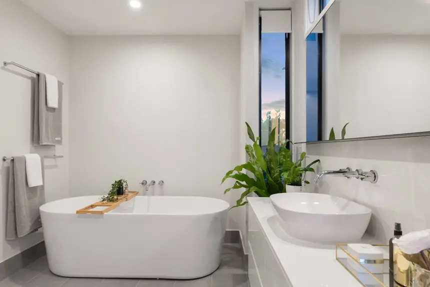 Bright all-white bathroom with a freestanding tub and chrome fixtures