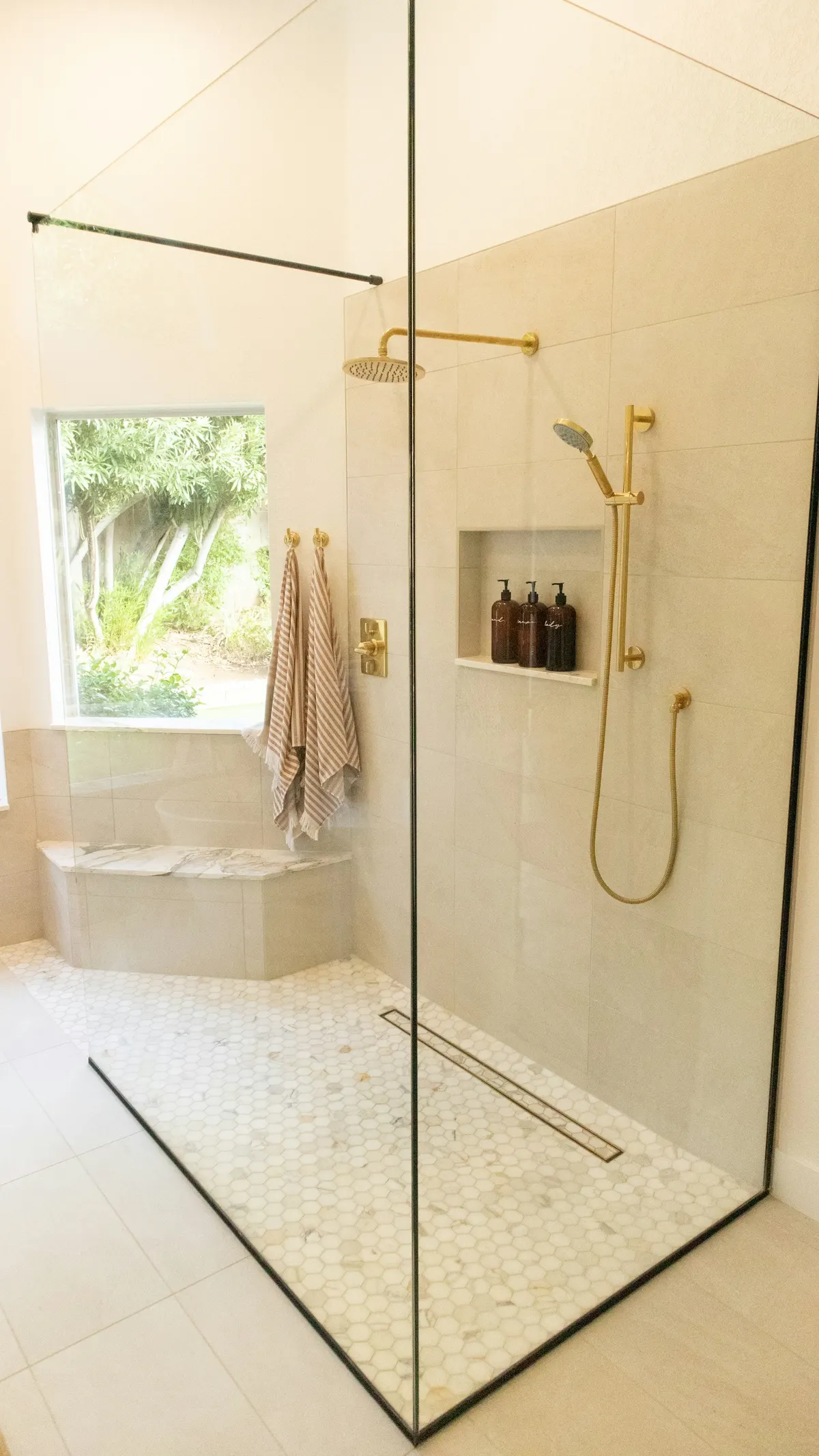 Walk-in shower with large-format tile and brushed-brass fixtures
